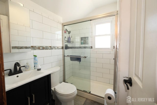 full bathroom featuring toilet, tasteful backsplash, tile walls, vanity, and a stall shower