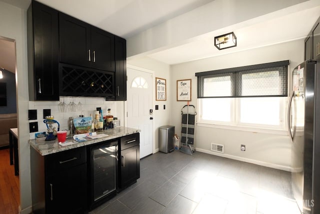 kitchen with freestanding refrigerator, beverage cooler, visible vents, and dark cabinetry