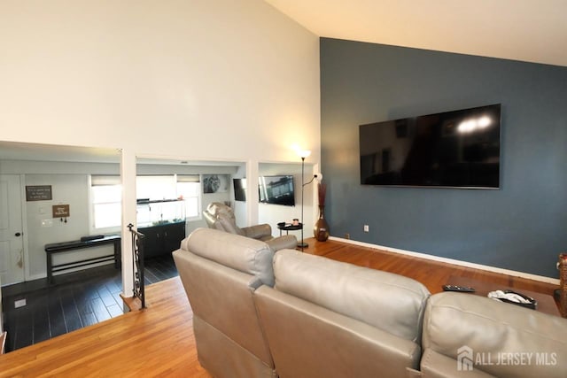 living area featuring light wood-style flooring, baseboards, and high vaulted ceiling