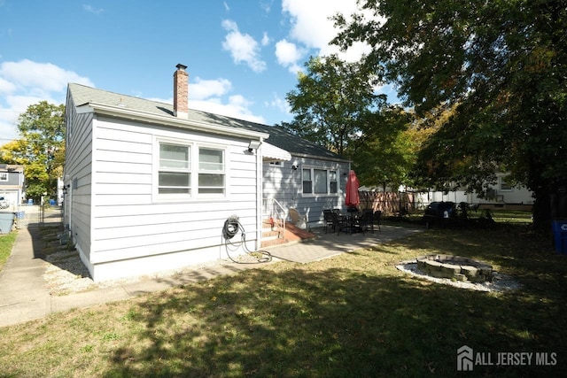 back of property with a patio, a fire pit, fence, a yard, and entry steps