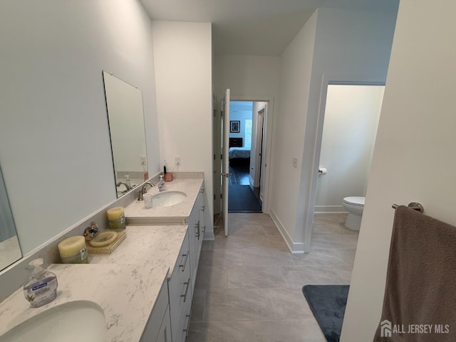 bathroom featuring ensuite bath, toilet, vanity, and baseboards