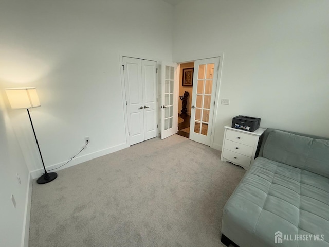 unfurnished bedroom featuring french doors, baseboards, a high ceiling, and carpet flooring