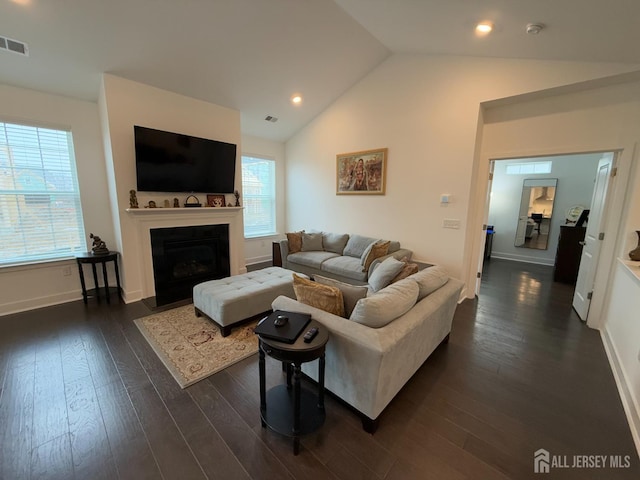 living area featuring visible vents, baseboards, a fireplace with flush hearth, vaulted ceiling, and dark wood-style floors