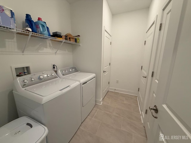 laundry area with light tile patterned floors, baseboards, washing machine and dryer, and laundry area