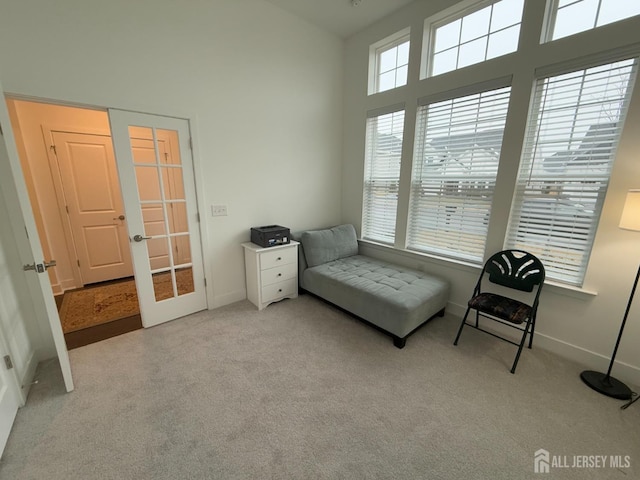 living area featuring french doors, baseboards, a high ceiling, and carpet