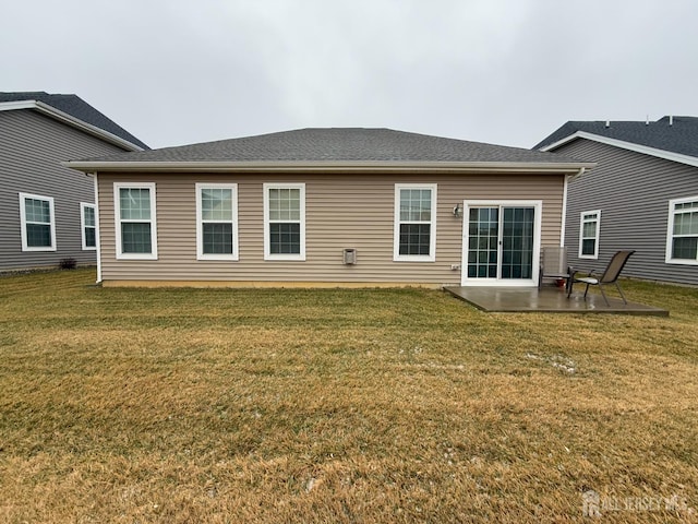 back of property with a yard, a patio area, and roof with shingles