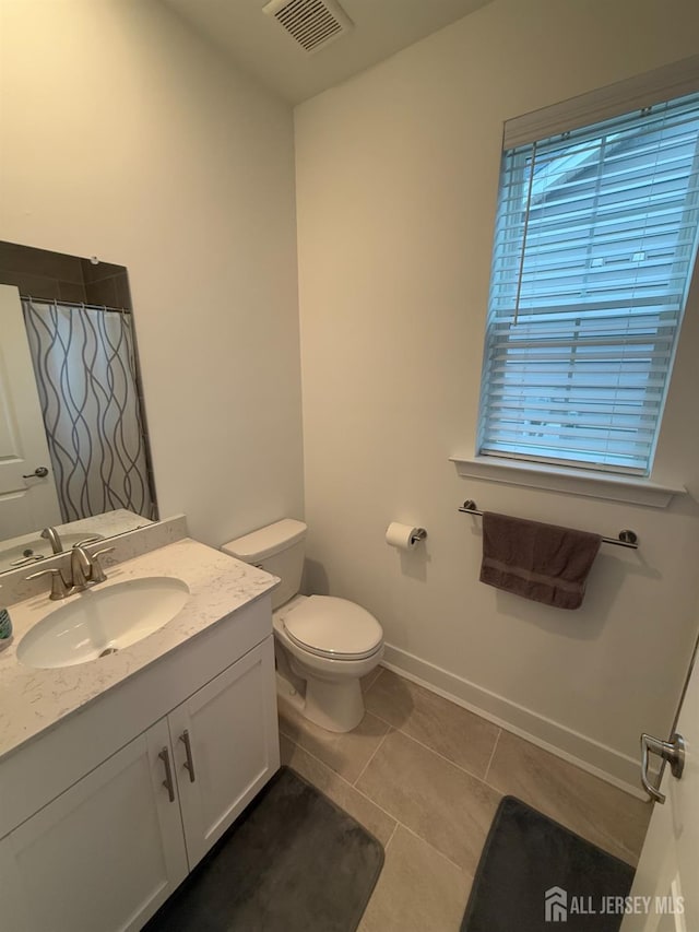 bathroom with vanity, baseboards, visible vents, tile patterned floors, and toilet