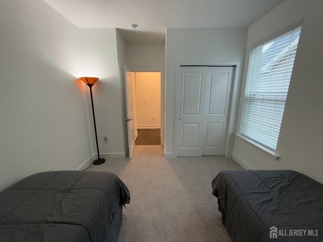 carpeted bedroom featuring a closet and baseboards