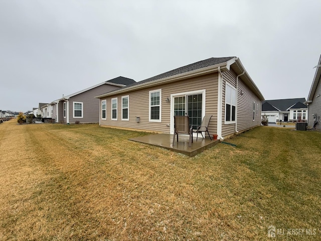 rear view of house featuring central AC unit, a yard, and a patio area