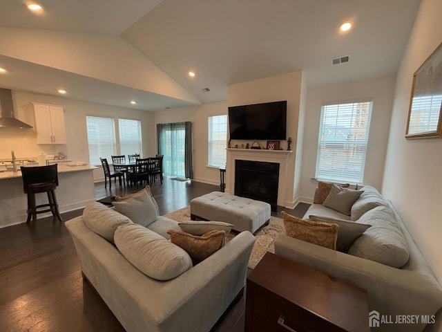 living area with visible vents, a healthy amount of sunlight, dark wood finished floors, vaulted ceiling, and recessed lighting