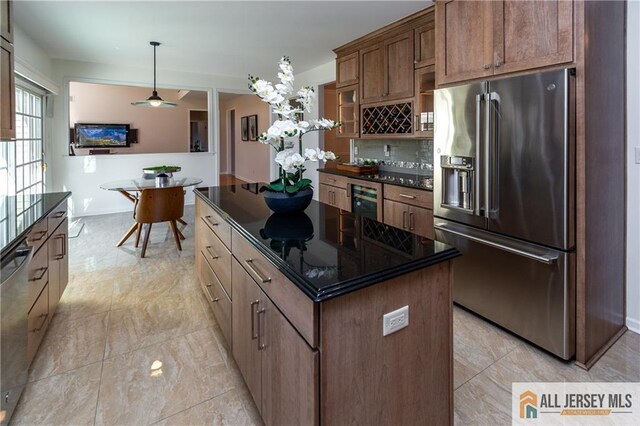 kitchen featuring pendant lighting, appliances with stainless steel finishes, backsplash, a center island, and wine cooler