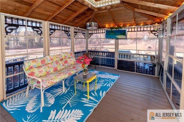 unfurnished sunroom with vaulted ceiling with beams, wooden ceiling, and plenty of natural light