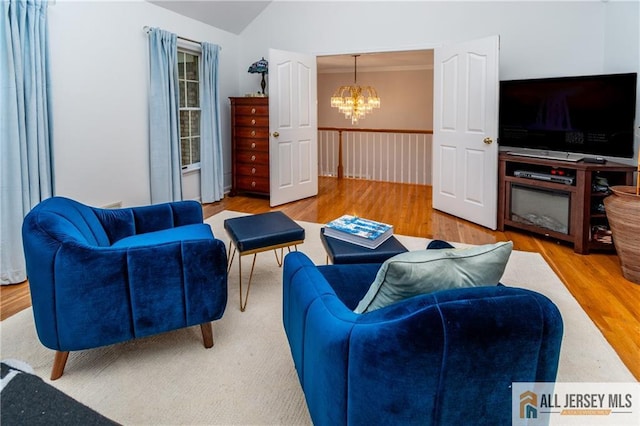 living room with a notable chandelier, crown molding, wood-type flooring, and vaulted ceiling