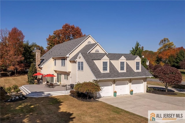 exterior space featuring a patio, a shingled roof, concrete driveway, a front yard, and a garage