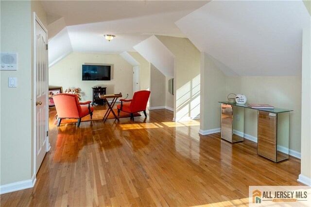 sitting room with vaulted ceiling, hardwood / wood-style floors, and baseboards