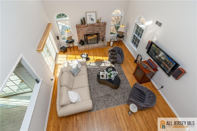 living room with a towering ceiling, wood-type flooring, and a fireplace