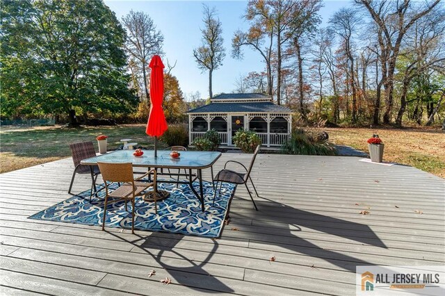 wooden terrace with outdoor dining area and a gazebo