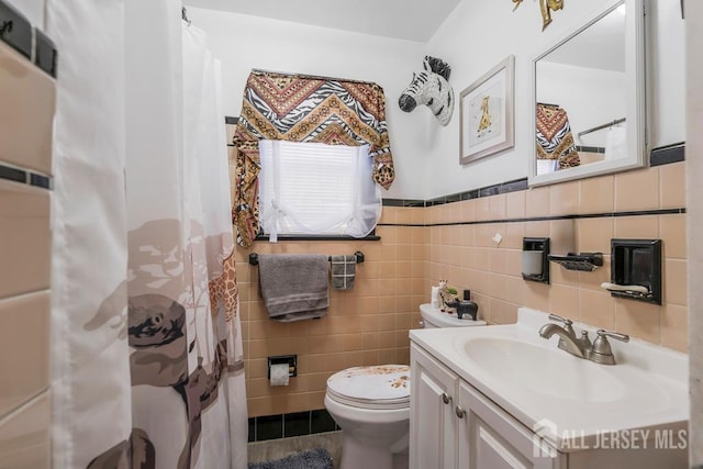 bathroom with a shower with shower curtain, vanity, toilet, and tile walls