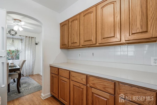 kitchen featuring backsplash, ceiling fan, and light hardwood / wood-style flooring