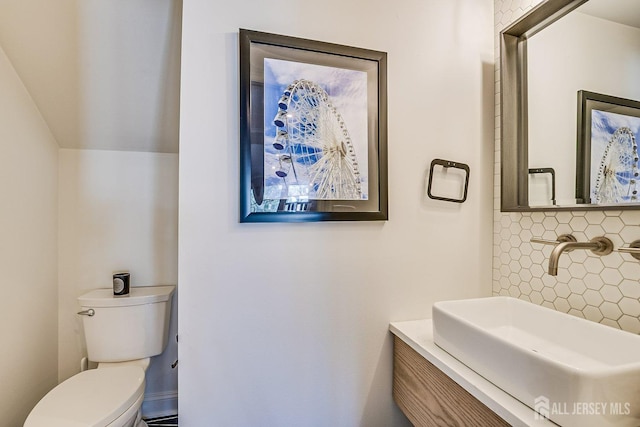 half bathroom featuring toilet, backsplash, and a sink