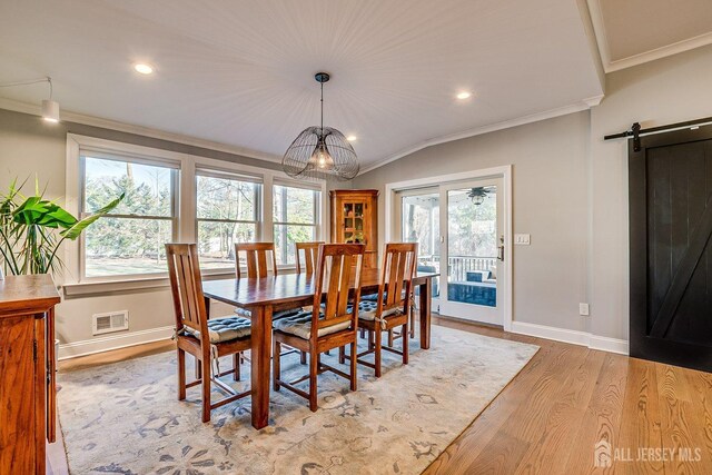 dining room with ornamental molding, baseboards, a barn door, visible vents, and wood finished floors
