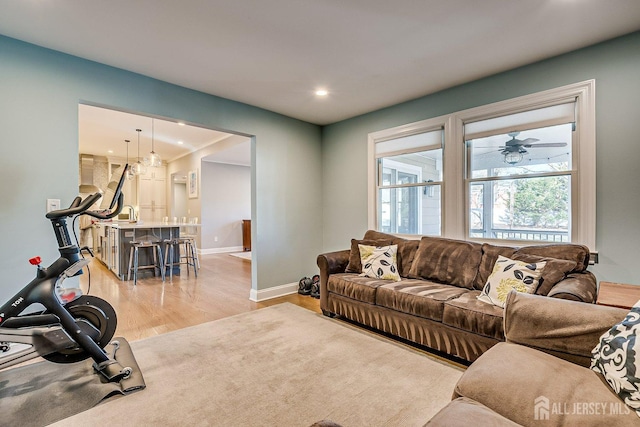 living area with recessed lighting, a ceiling fan, light wood-type flooring, and baseboards