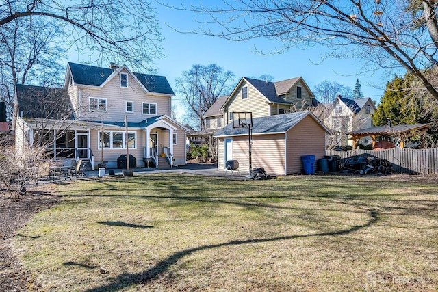 rear view of property with an outbuilding, a patio, fence, a yard, and a chimney