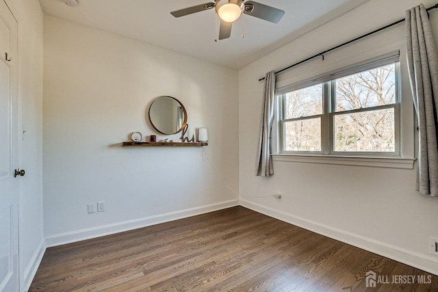 empty room featuring a ceiling fan, baseboards, and dark wood-style flooring