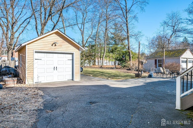 detached garage featuring aphalt driveway and fence