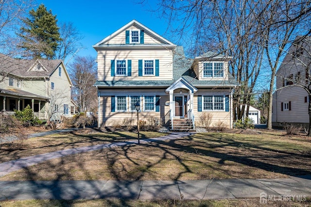 traditional home featuring a detached garage and a front lawn