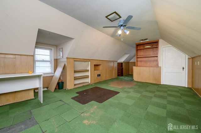 additional living space with a wainscoted wall, a ceiling fan, wooden walls, and lofted ceiling