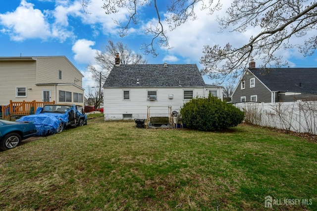 rear view of house with a chimney, fence, and a lawn
