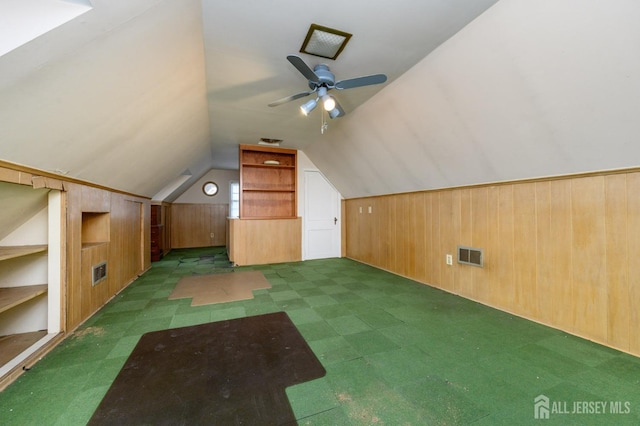 bonus room featuring visible vents, wood walls, built in shelves, and lofted ceiling