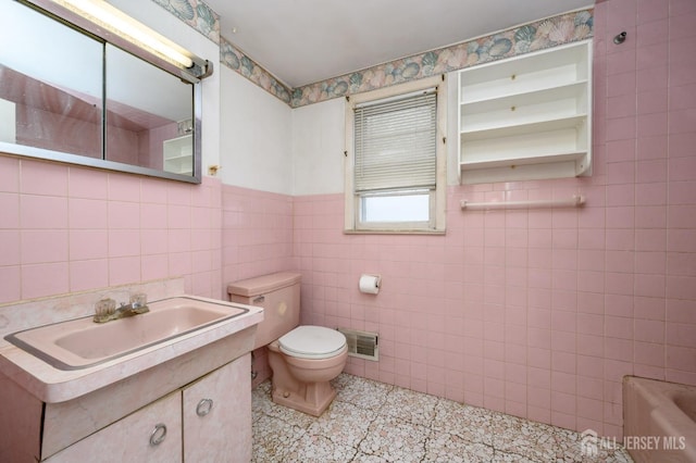 full bath with a tub, tile walls, toilet, vanity, and visible vents
