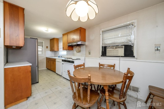 kitchen with under cabinet range hood, white appliances, brown cabinetry, cooling unit, and light countertops