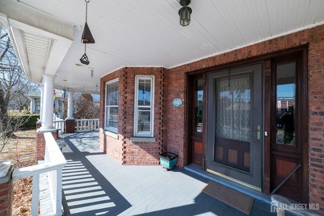 doorway to property with a porch and brick siding