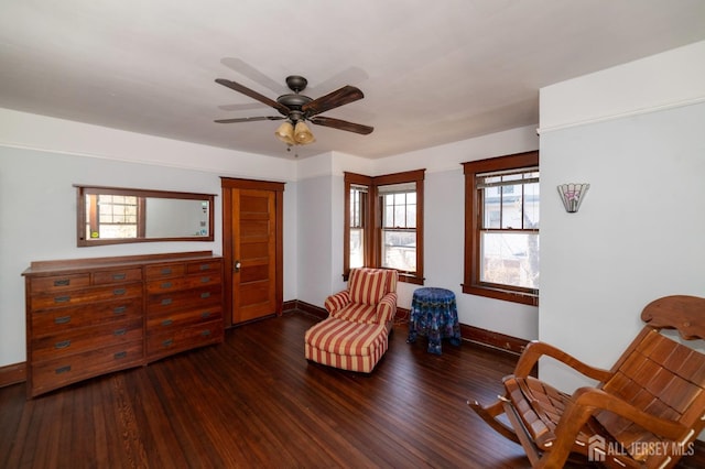 living area featuring a ceiling fan, baseboards, and hardwood / wood-style flooring