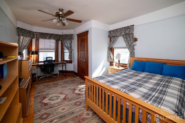 bedroom featuring a closet, multiple windows, baseboards, and wood finished floors