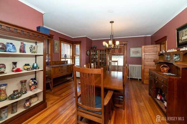 dining area featuring ornamental molding, radiator, a chandelier, and wood finished floors