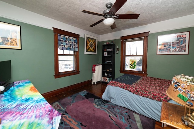 bedroom with baseboards, radiator, ceiling fan, wood finished floors, and a textured ceiling