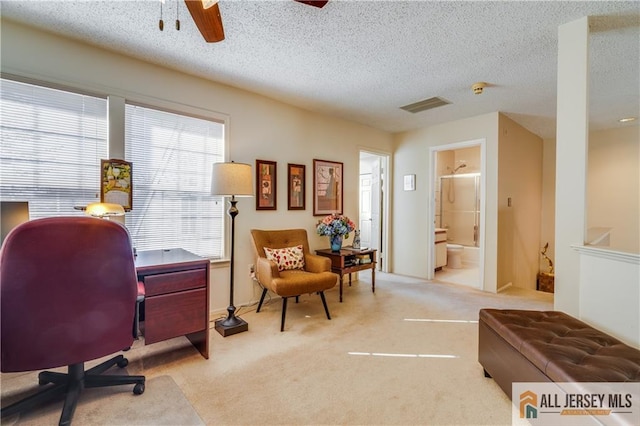 carpeted office space with ceiling fan, visible vents, and a textured ceiling