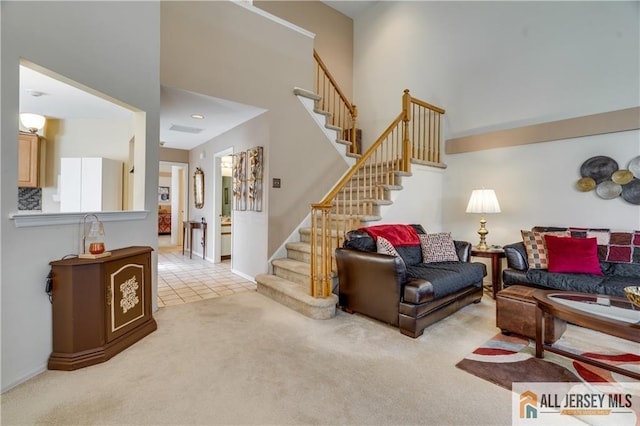 living room with light tile patterned flooring, light carpet, a towering ceiling, and stairs