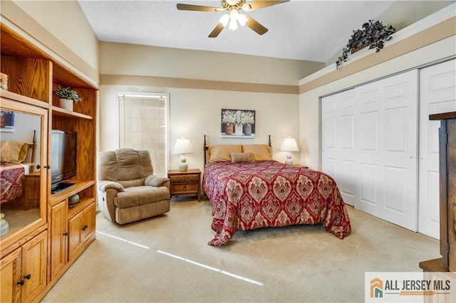 bedroom with a textured ceiling, ceiling fan, a closet, and light colored carpet