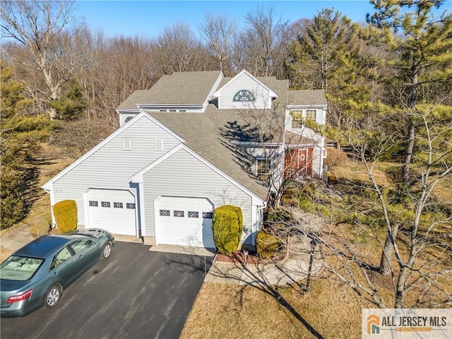 view of front of home with roof with shingles and driveway