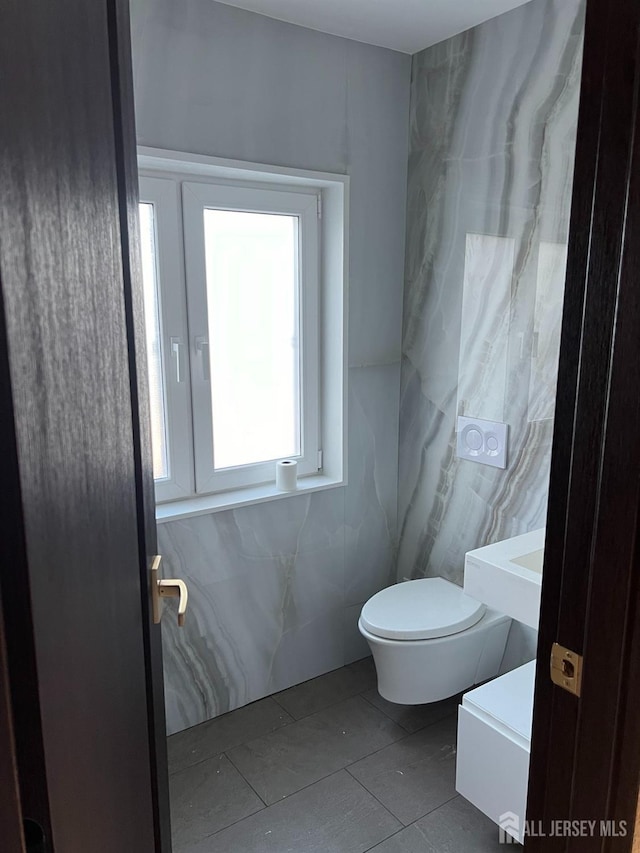 bathroom with tile patterned floors, toilet, and tile walls