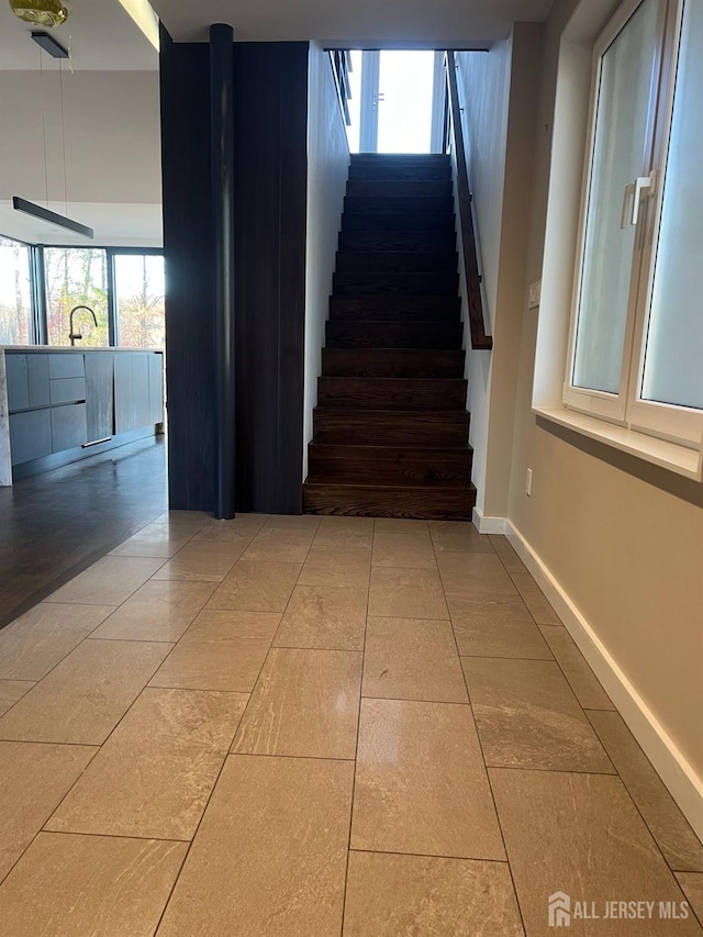 staircase featuring tile patterned floors and sink