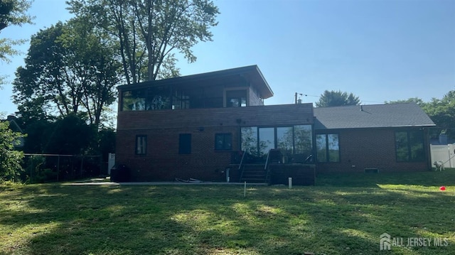 rear view of house featuring a sunroom and a lawn