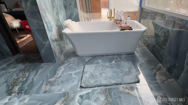 bathroom featuring tile walls and a tub to relax in