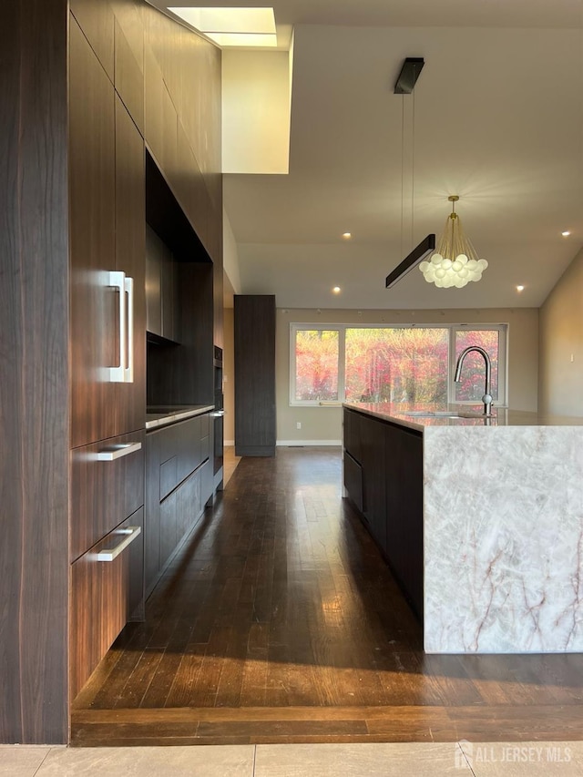 kitchen featuring an island with sink, sink, dark wood-type flooring, and pendant lighting