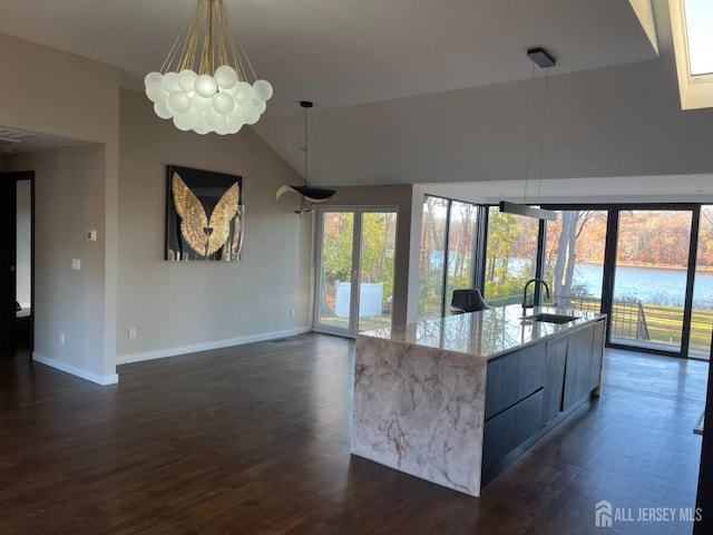 kitchen featuring vaulted ceiling, an island with sink, sink, dark hardwood / wood-style flooring, and a water view